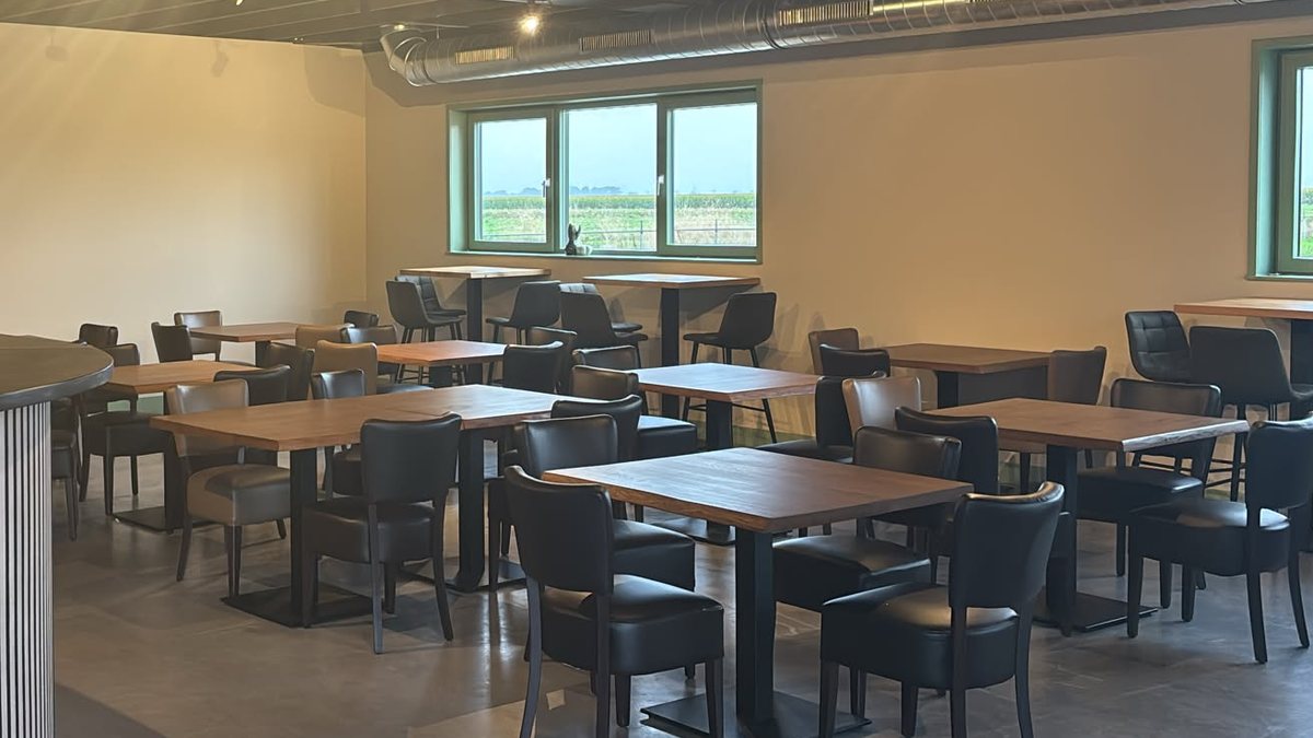 De zaal met tafels en uitzicht over het land